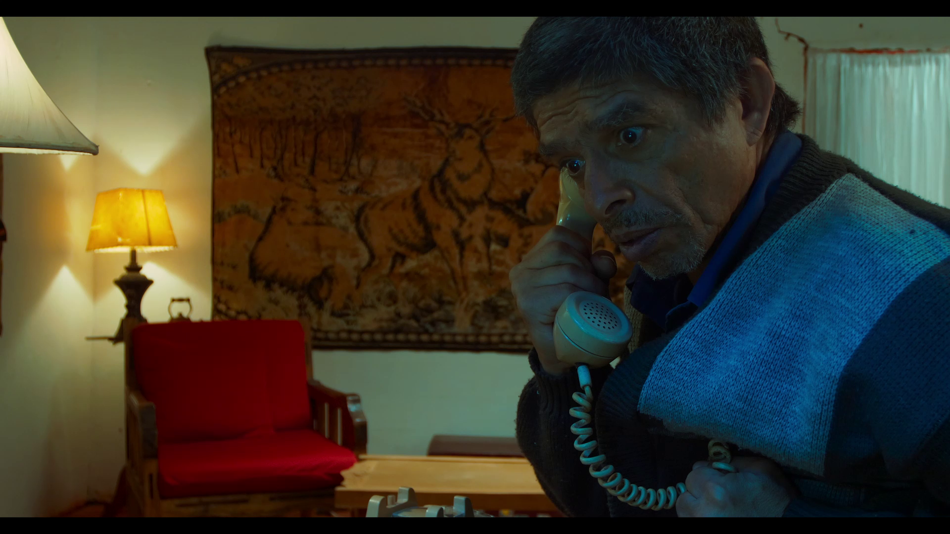 Production still showing a dramatic cinematic scene with intense lighting and shadows, characteristic of the noir aesthetic.